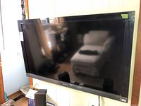 Front view of Sony 46" TV mounted on wall, showing screen reflection and black bezel with Sony logo.