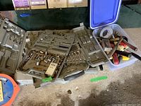 Overview of the contents showing plastic carrying cases for sockets and wrenches, plastic bin holding hammers, screwdrivers, and rolls of duct tape.