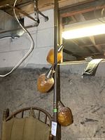 Side angle shot showing the tension pole with amber textured glass light shades attached, with metal adjustment fixtures.