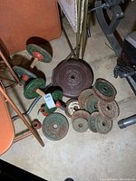 Photo showing various weight plates on floor with two dumbbells and a brown York plastic coated plate
