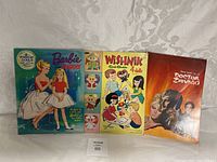 Photo showing three boxed vintage items: Barbie and Skipper stand-up dolls kit, Wishnik card game, and Doctor Zhivago booklet/book.