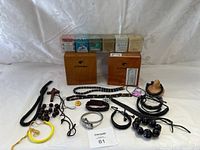 The entire lot displayed on a white background, showing two wooden Cohiba boxes, multiple cigar packs, and numerous bracelets and necklaces made from wood, beads, leather, and cords.