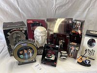 Overview photo of all Elvis Presley memorabilia items arranged on a white backdrop including figurines, clock, bust, PEZ dispensers, magazine, and memorabilia boxes.