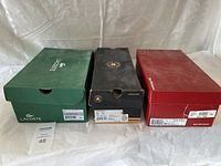 Three shoeboxes from Lacoste (green), Converse (black), Executive Imperials (red) aligned side-by-side with sizing labels visible showing size 13.