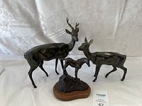 Photo showing all three metal deer statues: a stag, a doe, and a fawn on a wooden base.