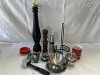 Photo of the full kitchen bundle showing pepper grinders, bowls, timer, lids, garlic press, napkin rings, and stand.