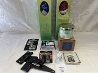 All items laid out on white surface showing full lot contents including hinges, batteries, ink cartridge, candles, hooks, figurine, candle jar, and coaster.