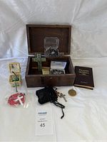 Overview of the religious bundle including wooden chest, prayer book, green ceramic cross, rosaries, and black pouches with jewelry