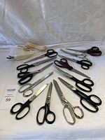 Full view of all scissors arranged on a white cloth including electric cutter.