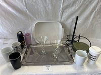 Front view of all items including the silver serving tray with two martini glasses, white rectangular baking dish, assorted mugs, water bottles, and black metal paper towel holder with green plates.