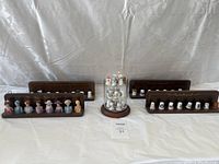 Wide view of four wooden display shelves each holding several ceramic and porcelain collectible thimbles of various sizes and decorations.