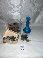 Lot showing blue glass decanter, brown carved figure under clear plastic, small box of metal pieces, and tattoo machine