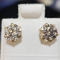 Close-up front view of two 10K yellow gold cubic zirconia stud earrings displayed on a white textured card.