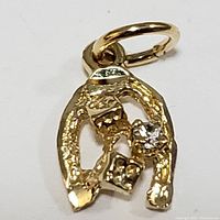 Close-up front view of 10K yellow gold horseshoe pendant with small clear stone and attachment bail.