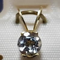 Close-up front view of the 14K yellow gold aquamarine pendant showing the faceted round gemstone and the gold bail.