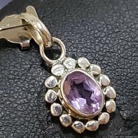 Close-up photo of the front side of the sterling silver amethyst pendant showing the oval faceted amethyst stone and silver decorative border.
