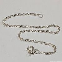 Photo of sterling silver chain bracelet laid flat showing link pattern and spring ring clasp