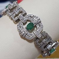 Close-up photo of the bracelet showing oval emerald stone surrounded by cubic zirconia stones in a sterling silver setting.