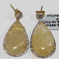 Front view of pair of golden rutile teardrop earrings in sterling silver setting, showing needle-like rutile inclusions and surrounding clear stones