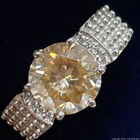 Close-up of sterling silver ring showing round 2.6 carat moissanite center stone and detailed band with accent stones and beaded design.