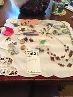 Full view of earrings spread on a white cloth, showing multiple pieces including clip-on and pierced earrings along with beaded necklace sets.