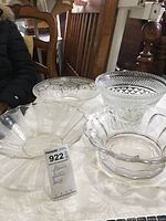 Four clear glass bowls arranged on a table, showing varying designs and flared rim edges.