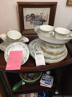Partial set of Lenox Oxford Bone China Fontaine pattern including plates, cups, saucers, and gravy boat with note and auction tag visible.