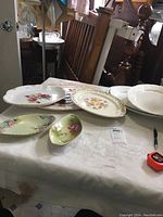 Multiple decorative ceramic platters displayed on a table, showing floral designs and shapes.