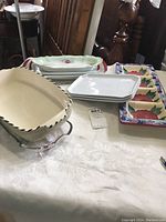 Overview of the collection showing various oblong dishes and platters on a table with a patterned cream tablecloth