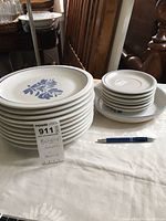 Stack of 10 dinner plates and stack of 6 saucers with 1 bowl under the saucers, all with blue floral design