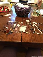 Overview of necklaces spread out on a wooden table showing various bead and chain styles in different colors.