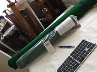 Photo showing two rolled green puzzle pads on a table with a keyboard and pen for scale.