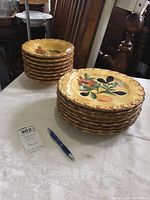 Stack of 8 scalloped edge dinner plates featuring Pompeii fruit pattern with pears, cherries, and leaves on yellowish background.