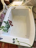 Large rectangular bowl with colorful botanical design and smooth edges, placed on newspaper