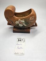 Side view of Roseville planter showing floral motif and curled top edge.