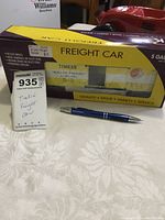 Photo of the boxed Timkin freight train car with a pen and auction lot tag in foreground.