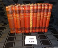 Photo of 11 Charles Dickens books standing upright, showing spines and titles.