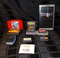 Photo showing Nintendo 64 cartridges Madden 64 and NBA Jam, PlayStation memory card, PSP UMD case for Tron, Game Boy Advance cartridges, and Sega cartridge