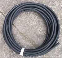 Full coiled electrical cable on concrete floor, black outer jacket, approximately 50 feet long.