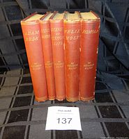 Front view showing packed spines of five hardcover George Eliot books with red cloth covers and gilt titles.