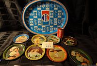 Photo showing a vintage Pepsi serving tray in oval shape, seven small vintage Coca-Cola round trays with artwork of women, and one Coca-Cola pencil sharpener resembling a soda can.