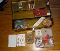 Overall view of the open metal tackle box showing various fishing hooks and lures.