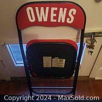 View of the backrest showing red fabric with 'OWENS' printed in white uppercase letters on black metal frame.
