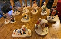 Photo showing the full set of 10 different Sebastian miniature figurines arranged on a wooden table, depicting various characters and scenes.
