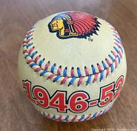 Close-up photo of the baseball showing the years 1946-52 with red and blue stitching and a Native American mascot logo.