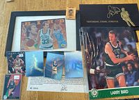 Photo showing multiple Larry Bird collectibles including hologram sets, two trading cards, 8x10 photo, matchbook, and framed collage card.