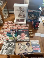 Lot of Boston Red Sox memorabilia displayed on a table including Roger Clemens statue, piggy bank, pins, photos, and wooden blocks.