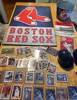 Full view of Boston Red Sox memorabilia, including large wall hanging, baseball cards, magazines, Beech Pale, and memorabilia arranged on table.
