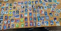 Top view of approximately 100 baseball cards spread out on a wooden surface showing variety of players including Derek Jeter and Nolan Ryan