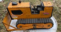 Side angle photo of vintage yellow metal Tonka bulldozer showing wear and Tonka logo.